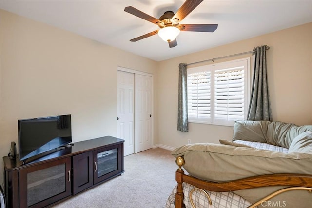 bedroom featuring baseboards, a closet, a ceiling fan, and light colored carpet