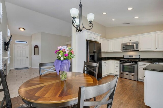 dining area featuring sink, vaulted ceiling, a chandelier, and light wood-type flooring