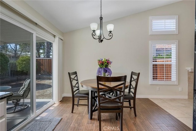 dining room featuring an inviting chandelier, hardwood / wood-style flooring, and vaulted ceiling