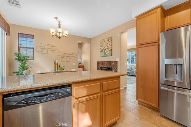 kitchen featuring pendant lighting, light tile patterned floors, stainless steel appliances, a notable chandelier, and a fireplace