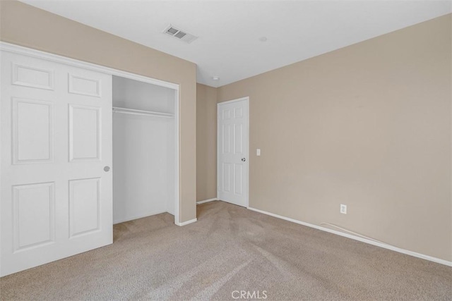 unfurnished bedroom with light colored carpet and a closet