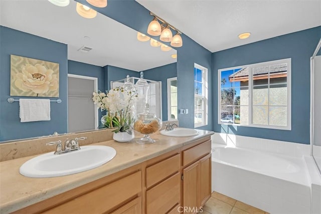 bathroom featuring tiled tub, vanity, and tile patterned floors