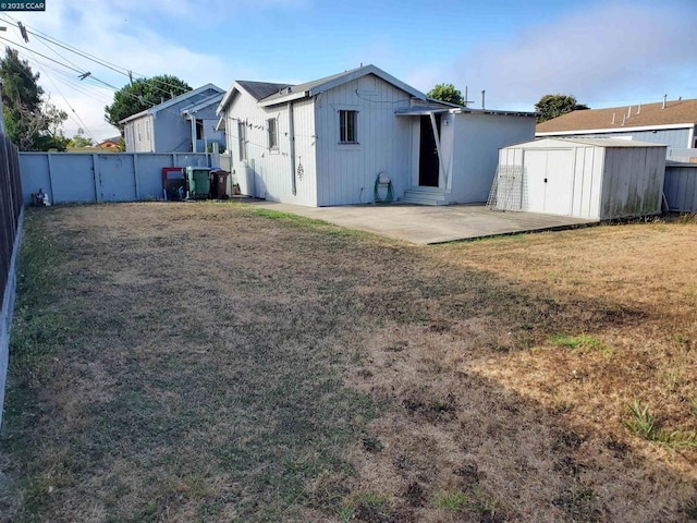 back of property featuring a patio, a shed, and a lawn