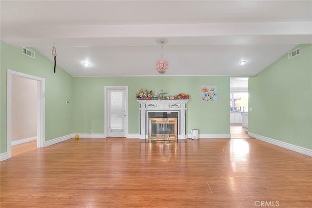 unfurnished living room featuring lofted ceiling with beams and light wood-type flooring