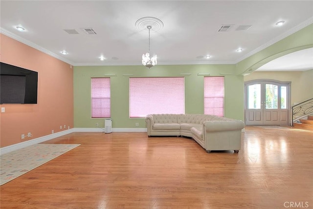 unfurnished living room with a notable chandelier, crown molding, and light hardwood / wood-style floors