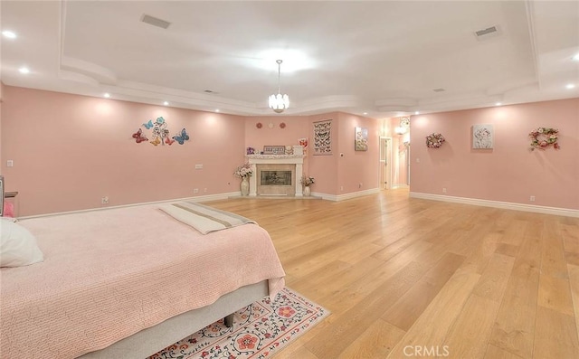 bedroom with a tray ceiling and light wood-type flooring