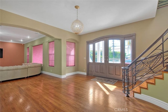 foyer with hardwood / wood-style floors, crown molding, and a chandelier