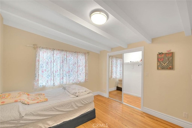 bedroom featuring wood-type flooring, lofted ceiling with beams, and a closet