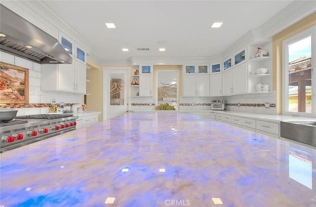 kitchen with crown molding, double oven range, extractor fan, and white cabinets