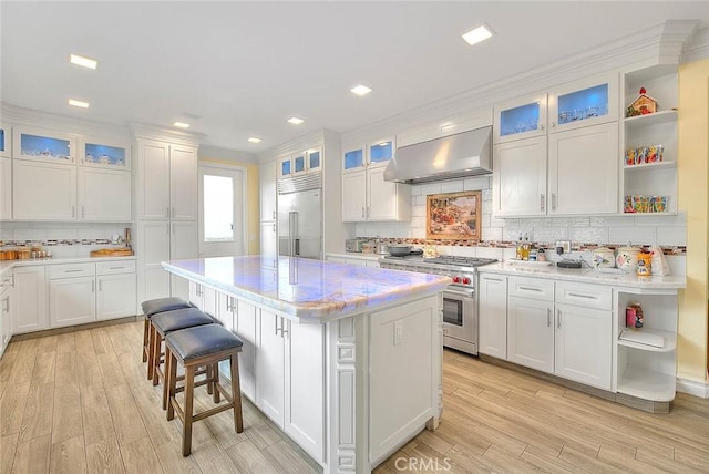 kitchen featuring white cabinetry, high quality appliances, a center island, and exhaust hood