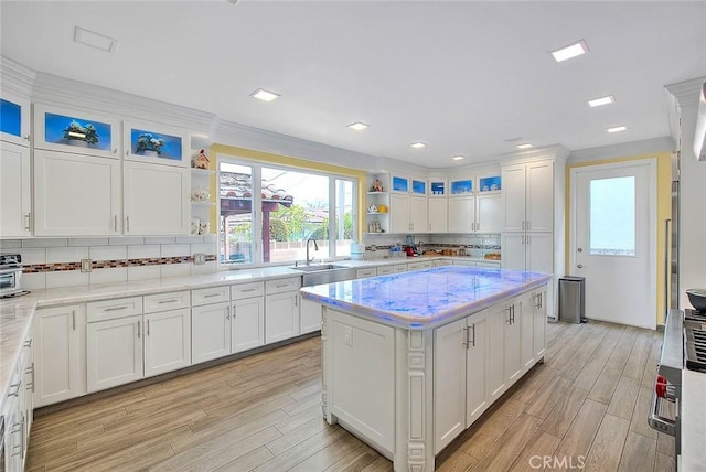 kitchen featuring white cabinetry, a kitchen island, sink, and light stone counters