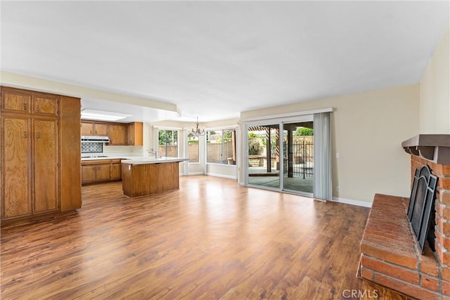 living room with wood-type flooring, a brick fireplace, and a notable chandelier