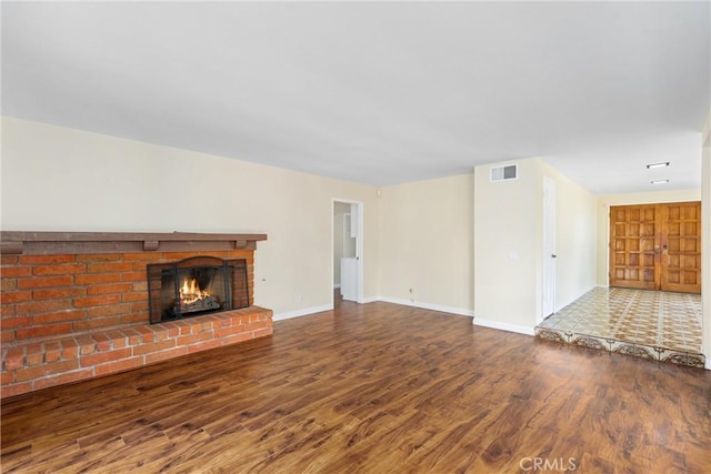 unfurnished living room with dark wood-type flooring and a fireplace