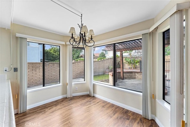 unfurnished dining area with hardwood / wood-style floors, a chandelier, and a healthy amount of sunlight