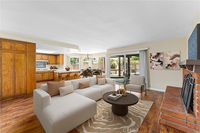 living room with dark hardwood / wood-style floors, a brick fireplace, and a wealth of natural light