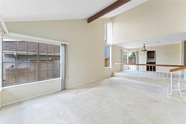 empty room with beamed ceiling, high vaulted ceiling, and carpet