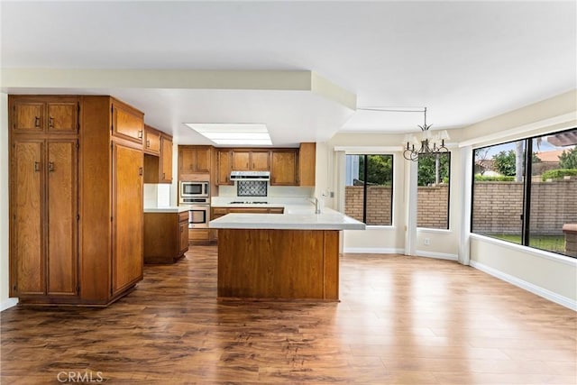 kitchen with stainless steel appliances, dark hardwood / wood-style floors, pendant lighting, and an inviting chandelier