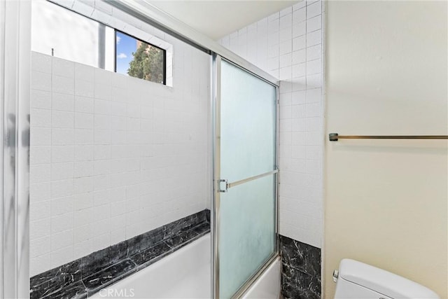 bathroom with toilet and combined bath / shower with glass door