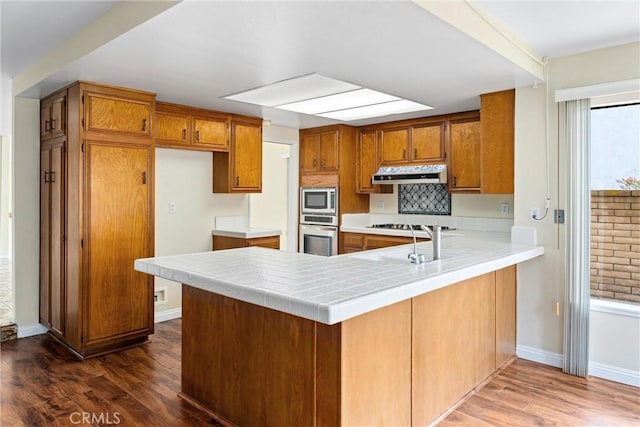 kitchen featuring sink, dark hardwood / wood-style floors, stainless steel appliances, and kitchen peninsula