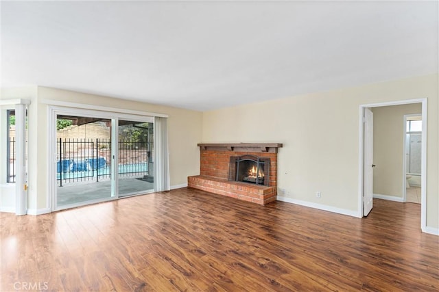 unfurnished living room with hardwood / wood-style floors and a brick fireplace