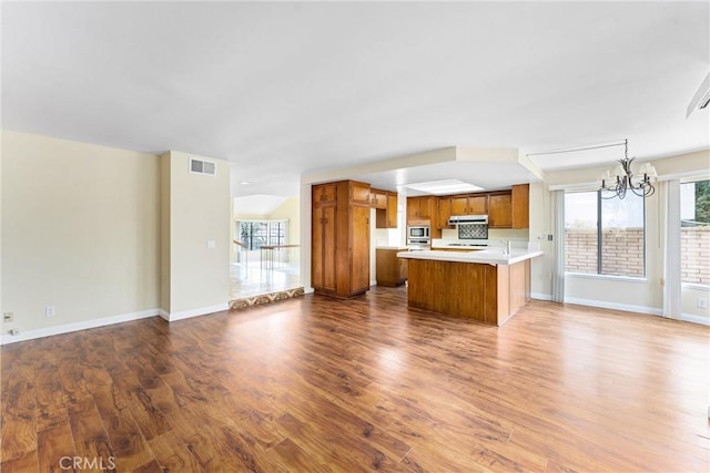 kitchen with hardwood / wood-style flooring, a center island, stainless steel microwave, decorative light fixtures, and a chandelier