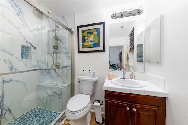 bathroom featuring toilet, vanity, and a marble finish shower