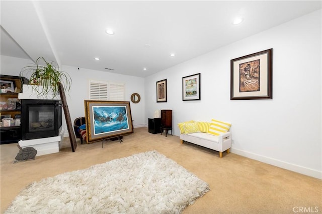 sitting room with recessed lighting, baseboards, light colored carpet, and a multi sided fireplace