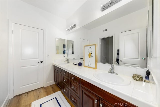 full bath with double vanity, wood finished floors, a sink, and visible vents