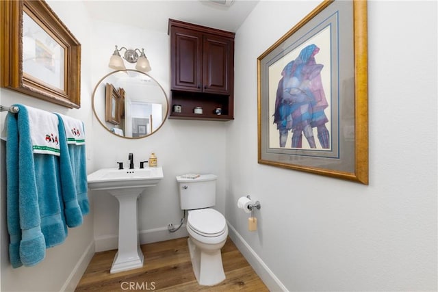 bathroom with wood finished floors, toilet, and baseboards