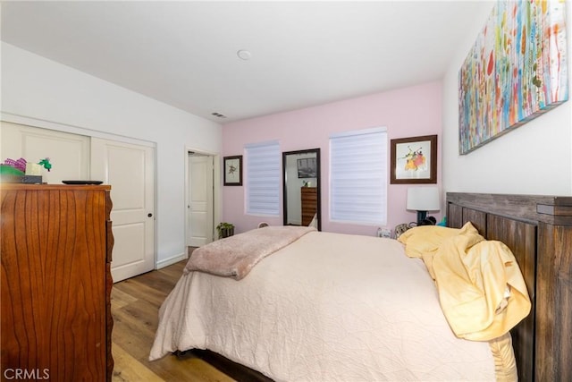 bedroom with a closet, visible vents, and light wood-style floors