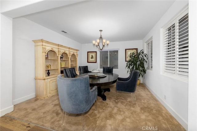 dining room featuring visible vents, light carpet, baseboards, and an inviting chandelier