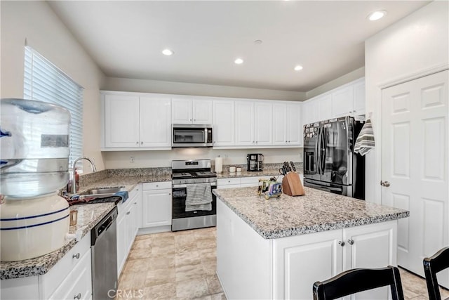 kitchen featuring stainless steel appliances, white cabinetry, a kitchen island, and sink