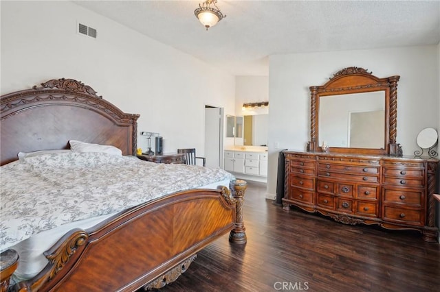 bedroom with dark hardwood / wood-style floors and ensuite bath