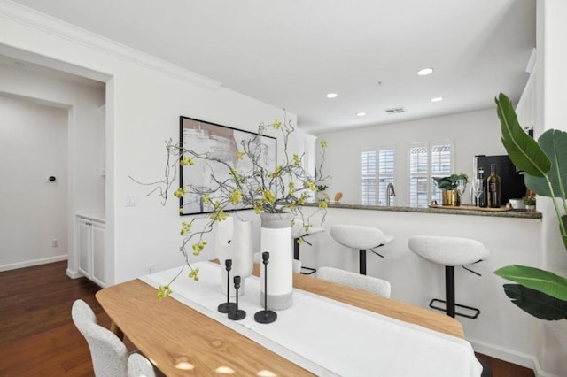 bar with sink, dark wood-type flooring, black refrigerator, ornamental molding, and white cabinets