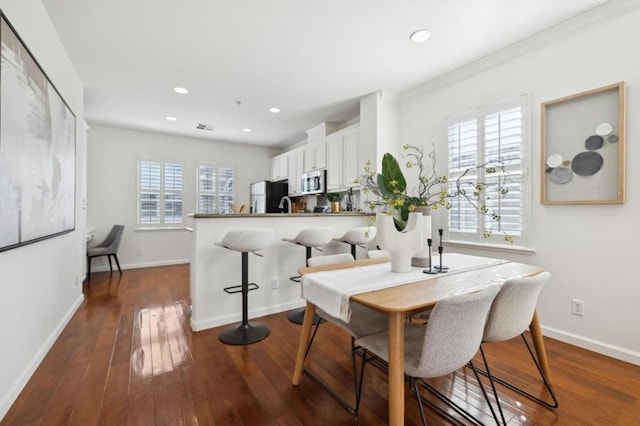 dining area with ornamental molding and dark hardwood / wood-style floors