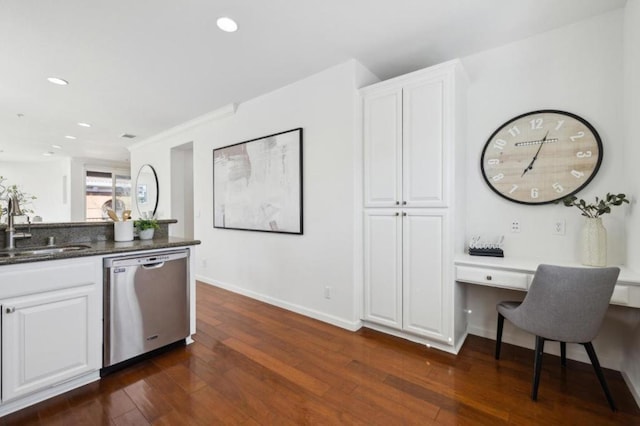 kitchen with dark wood-type flooring, sink, built in desk, stainless steel dishwasher, and white cabinets