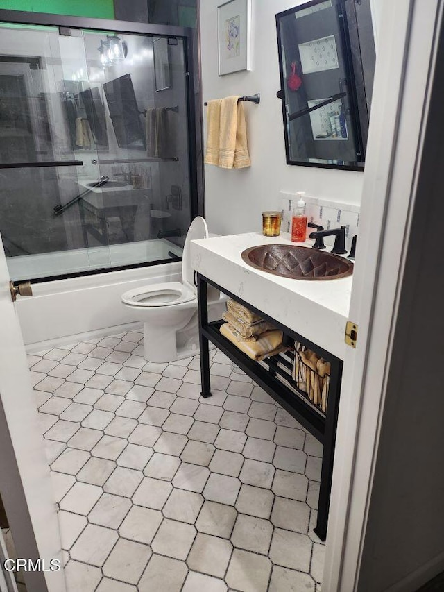 full bathroom with enclosed tub / shower combo, sink, and toilet