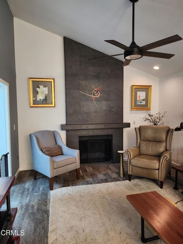 living room with lofted ceiling, dark wood-type flooring, a large fireplace, and ceiling fan