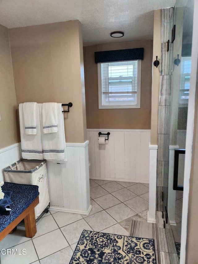 bathroom with a shower with shower door, tile patterned floors, and a textured ceiling