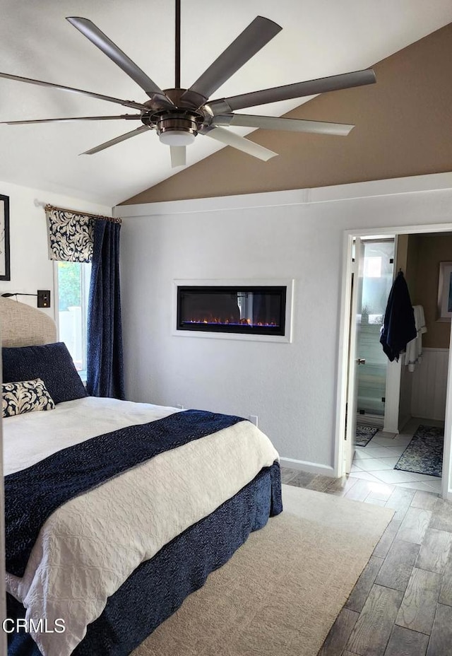 bedroom with ceiling fan, connected bathroom, and vaulted ceiling