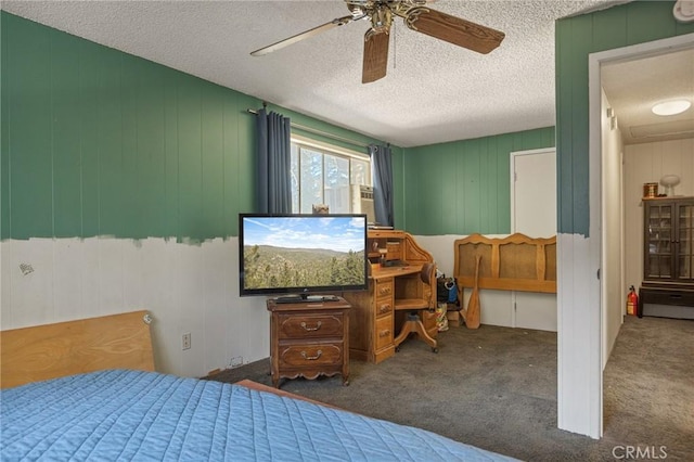 bedroom featuring dark carpet, a textured ceiling, ceiling fan, and wood walls