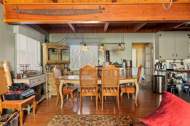 dining area with hardwood / wood-style flooring, wooden walls, and beam ceiling