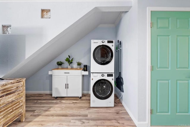 laundry room featuring cabinets, stacked washer / drying machine, and light hardwood / wood-style flooring