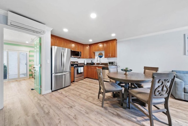 kitchen featuring an AC wall unit, sink, ornamental molding, stainless steel appliances, and light hardwood / wood-style flooring