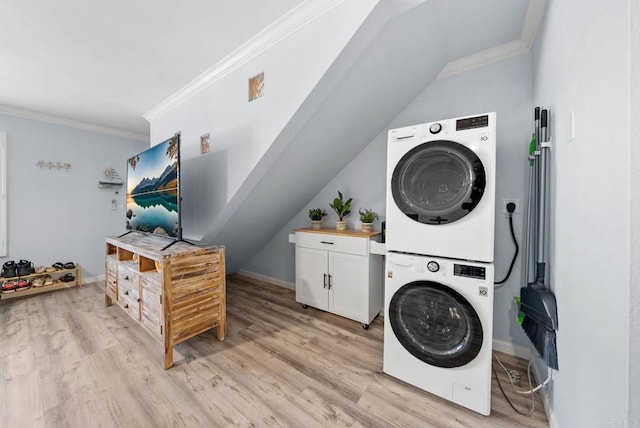 laundry area featuring crown molding, cabinets, stacked washing maching and dryer, and light hardwood / wood-style floors