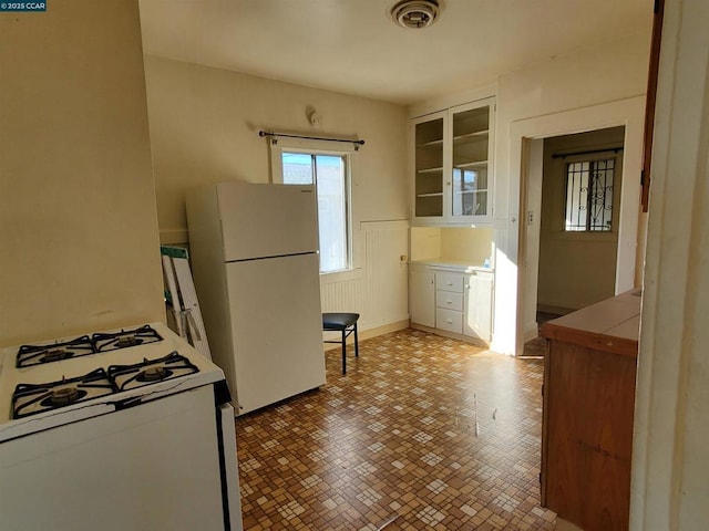 kitchen featuring white appliances, tile countertops, built in shelves, and white cabinets