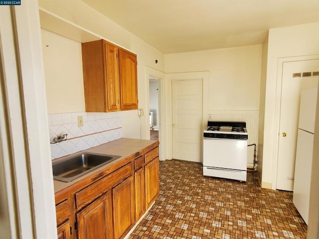 kitchen featuring white appliances, tile countertops, sink, and decorative backsplash