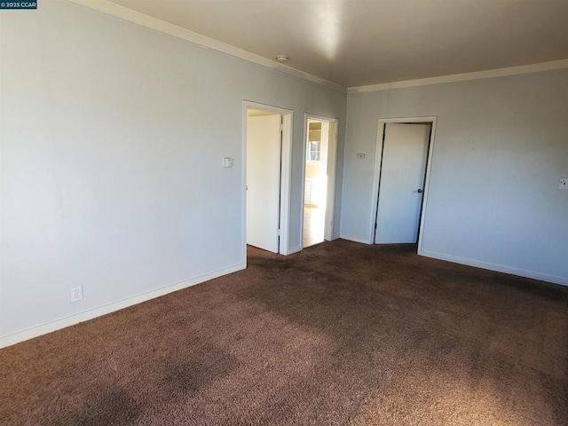 spare room featuring crown molding and dark carpet