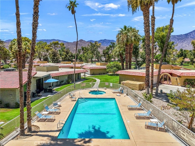 pool with a patio area, a hot tub, fence, and a mountain view