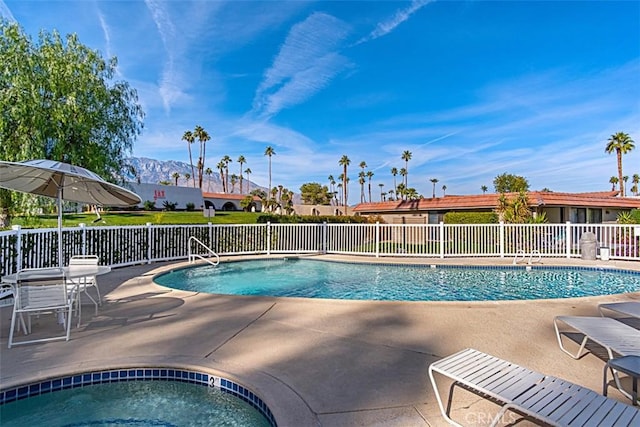 community pool with fence, a patio, and a mountain view